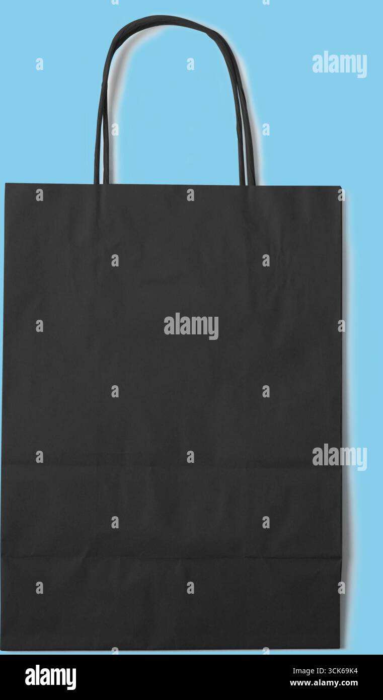 Un sac en papier noir Uni avec deux poignées, adapté pour transporter des objets ou des cadeaux. Banque D'Images