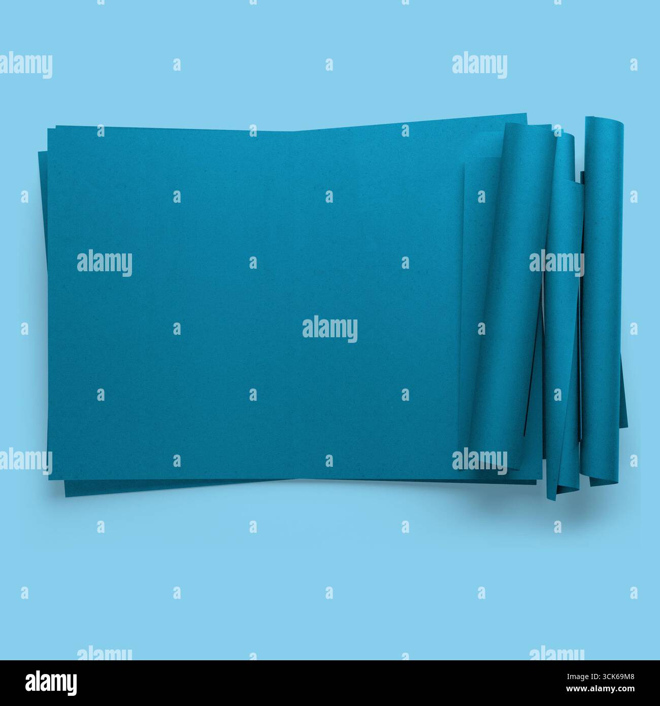 Une pile de feuilles de papier turquoise, certaines roulées, adaptées à l'artisanat ou aux projets artistiques. Banque D'Images