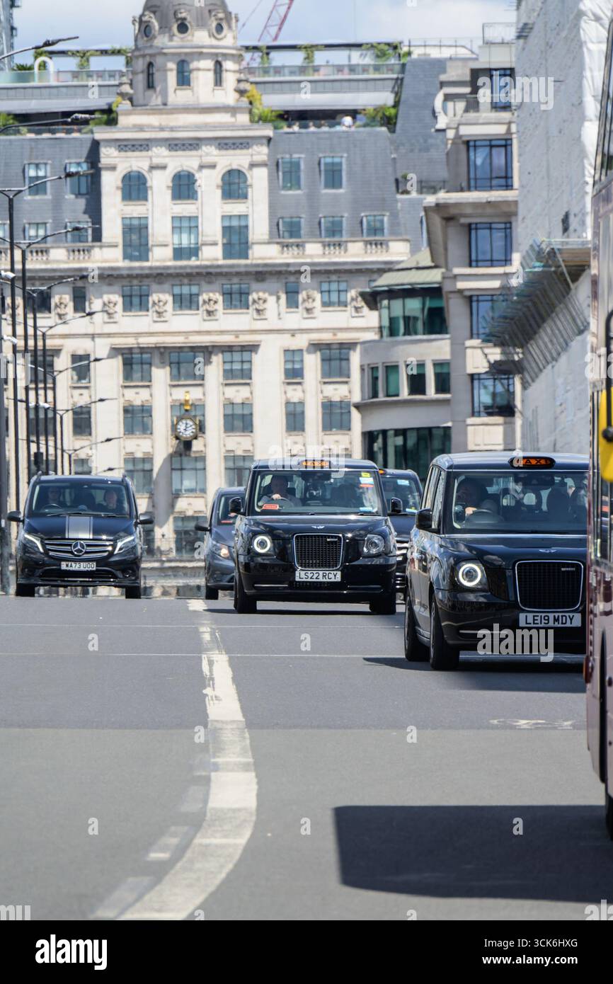 Londres, Royaume-Uni. Taxis noirs londoniens traversant London Bridge, vu du sud. Banque D'Images