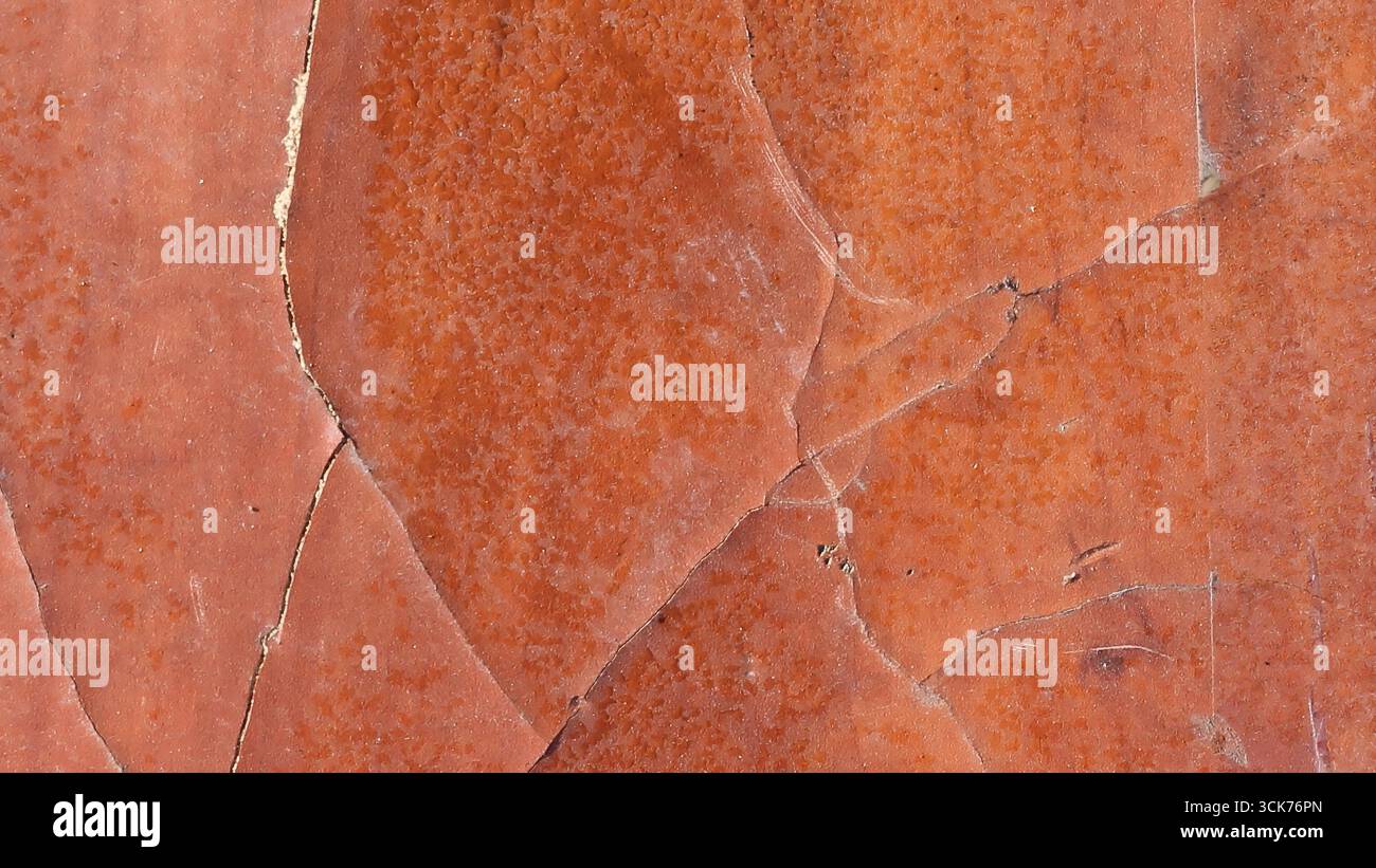 Un gros plan de la surface texturée de roche brun rougeâtre présentant des motifs naturels et des fissures. Banque D'Images