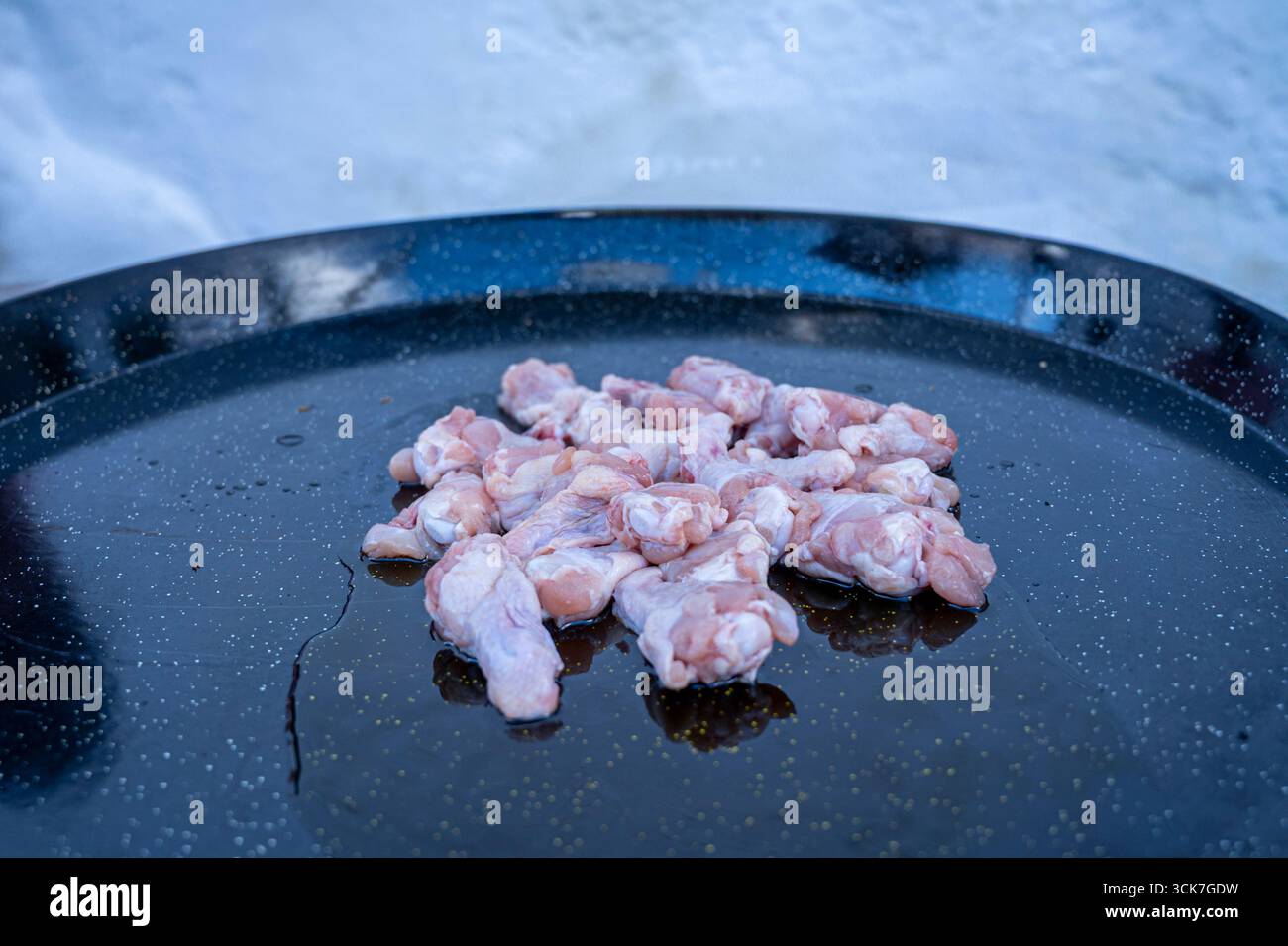 Une assiette d'ailes de poulet est sur une poêle noire. Les ailes de poulet sont coupées en petits morceaux et étalées sur la poêle Banque D'Images