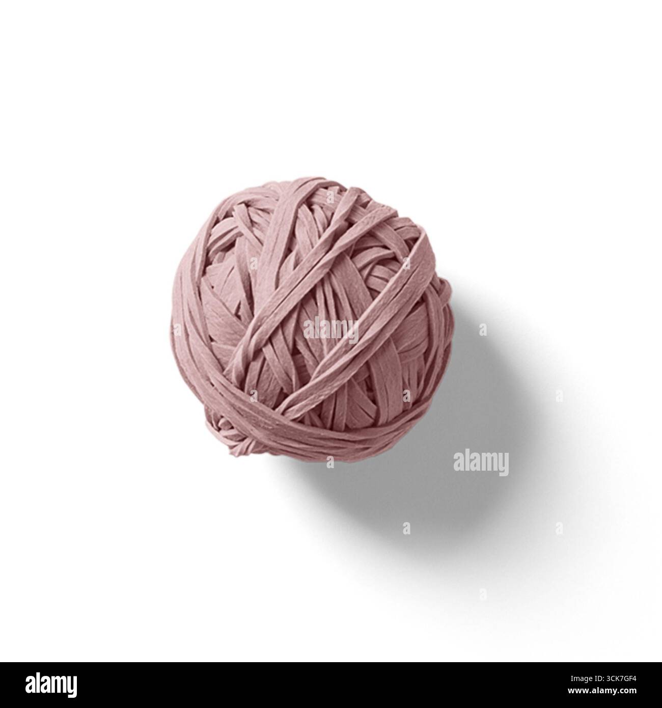 Une boule rose de matériau élastique, ressemblant à une boule de bande de caoutchouc, projetant une ombre douce sur un fond blanc. Banque D'Images