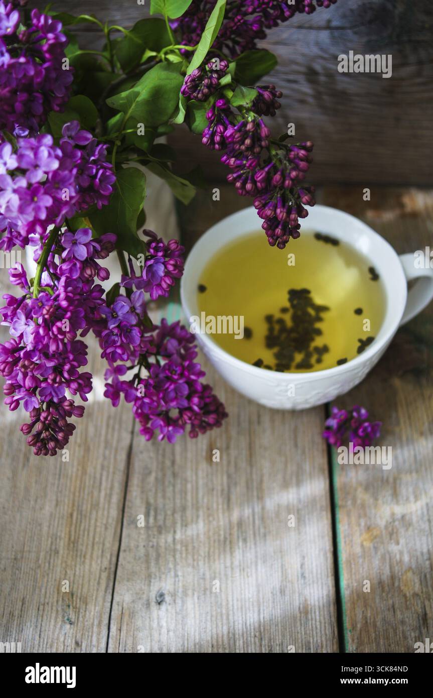 Fleurs lilas en pot et une tasse de thé à l'intérieur rustique Banque D'Images