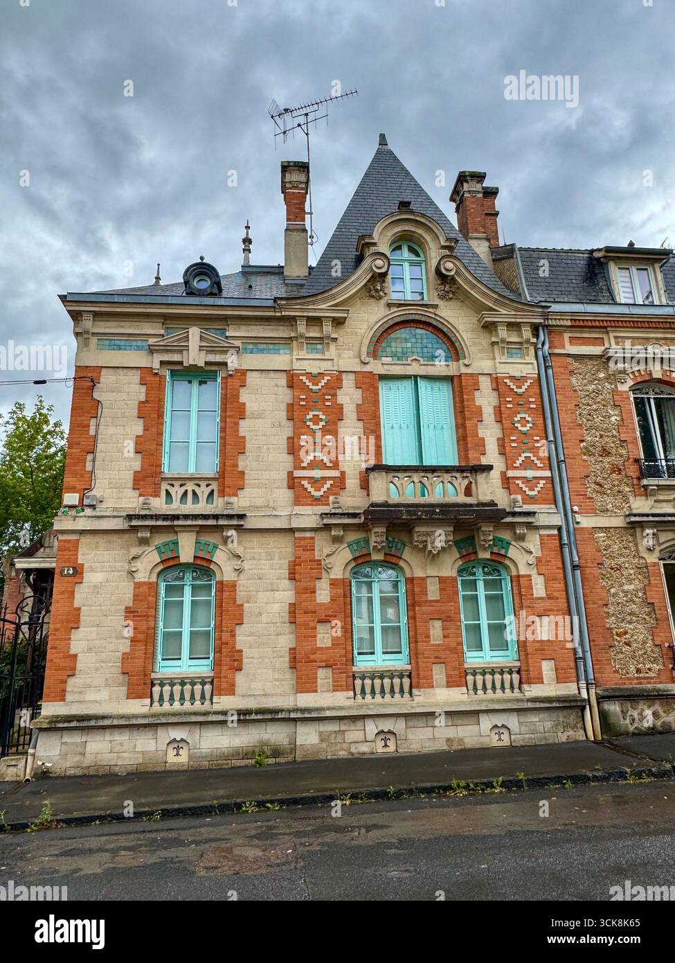 Élégante façade historique européenne avec brique rouge, pierre claire, volets bleus, sculptures ornées et toit en ardoise abrupte avec lucarnes - Image de stock capturée avec un smartphone