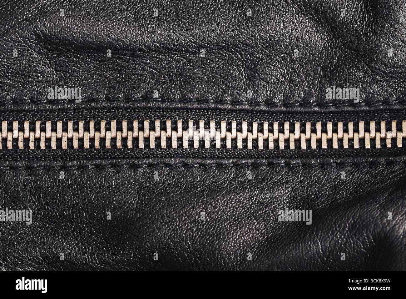 Texture en cuir noir avec fermeture éclair. Gros plan d'une attache métallique brillante. Détail de mode de l'accessoire vestimentaire. Fond matériel pour la conception. Banque D'Images