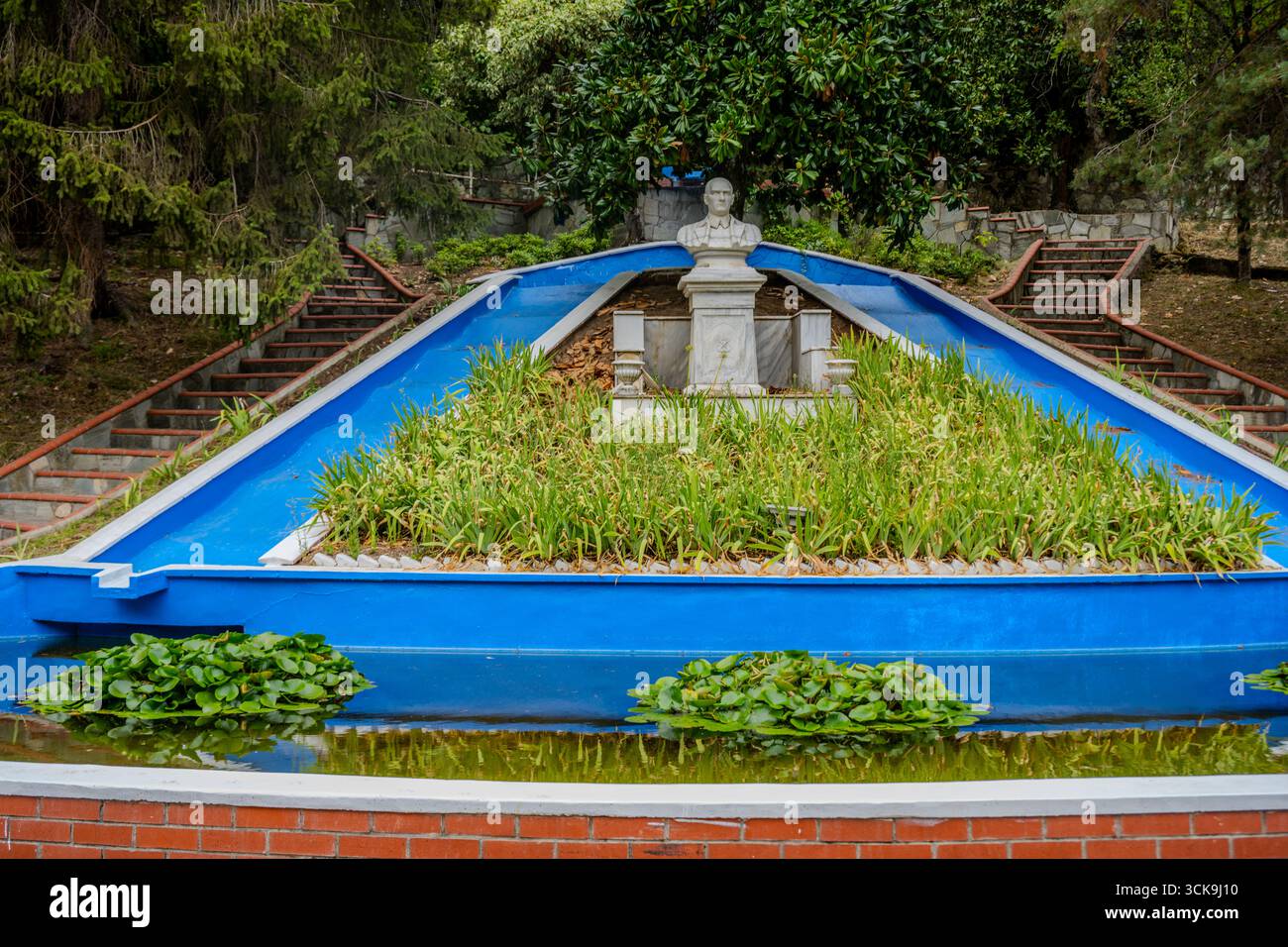 Monument en marbre blanc situé au-dessus d'une fontaine décorative bleue et entouré de verdure dans le parc thermal de Termal, Yalova, Türkiye. Banque D'Images