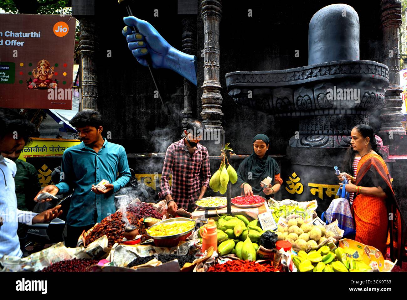 Un vendeur de rue est vu vendre des fruits devant un Pandal (lieu de culte temporaire) à Mumbai. Banque D'Images Un vendeur de rue est vu vendre des fruits devant un Pandal (lieu de culte temporaire) à Mumbai. Banque D'Images