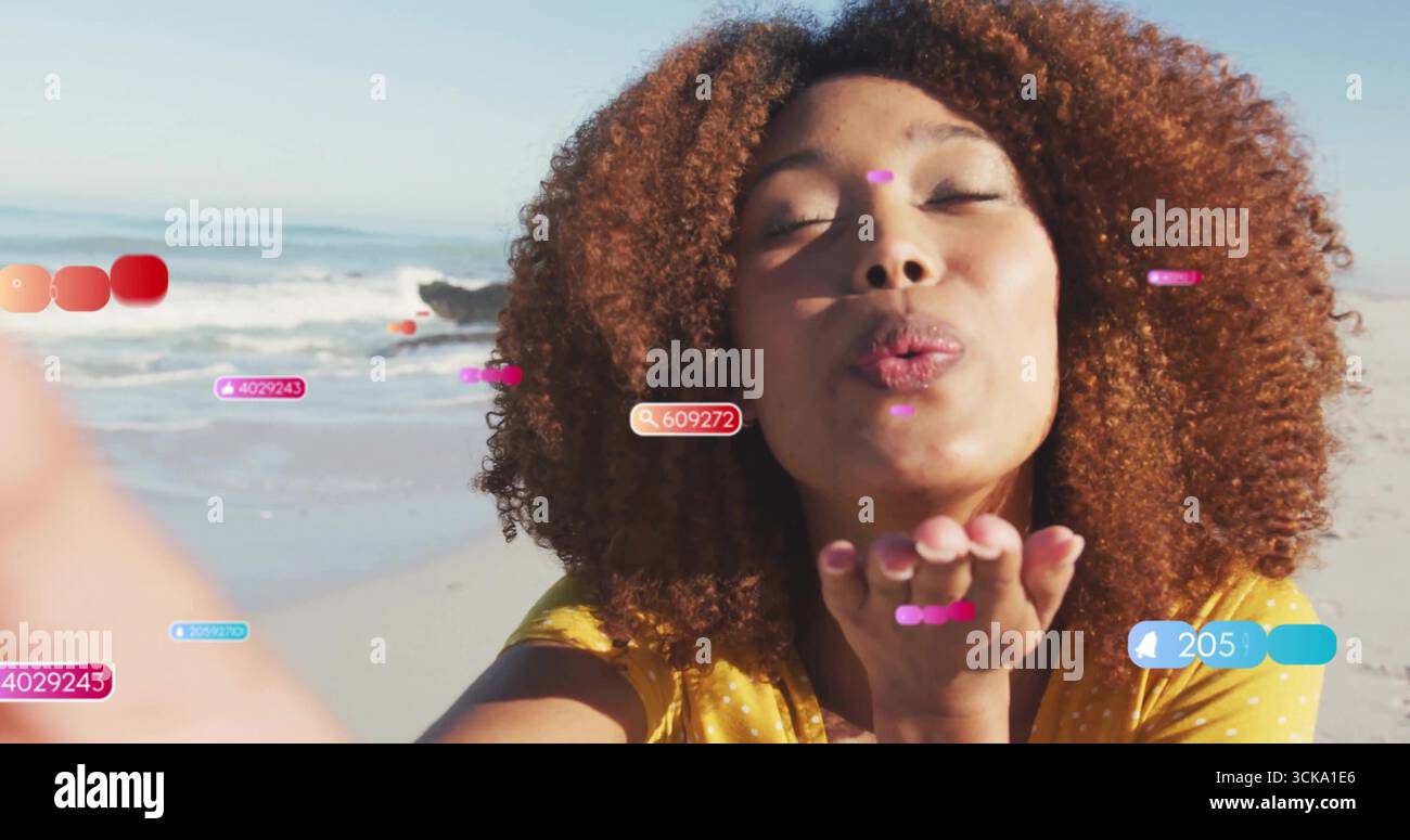 Femme portant le baiser de soufflage de haut jaune sur la plage avec des icônes de notification flottantes, étiquettes numériques Banque D'Images