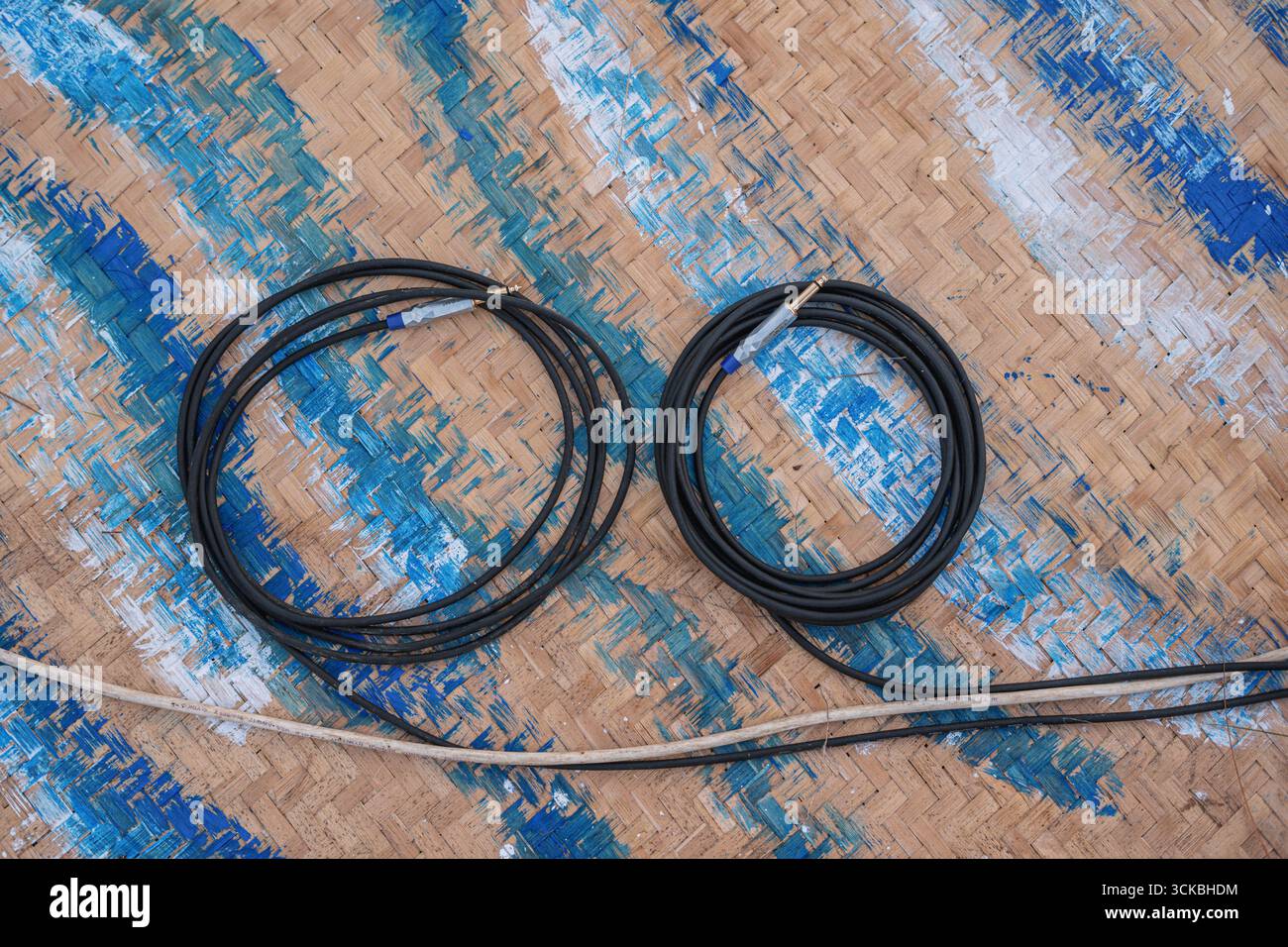Deux câbles noirs enroulés sur un tapis tissé avec des motifs bleus et blancs Banque D'Images