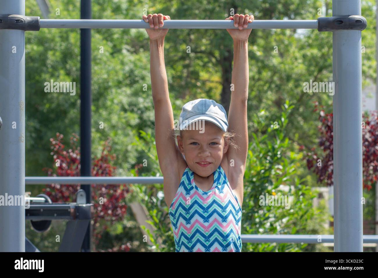 Fille suspendue sur la barre horizontale à Playground Banque D'Images