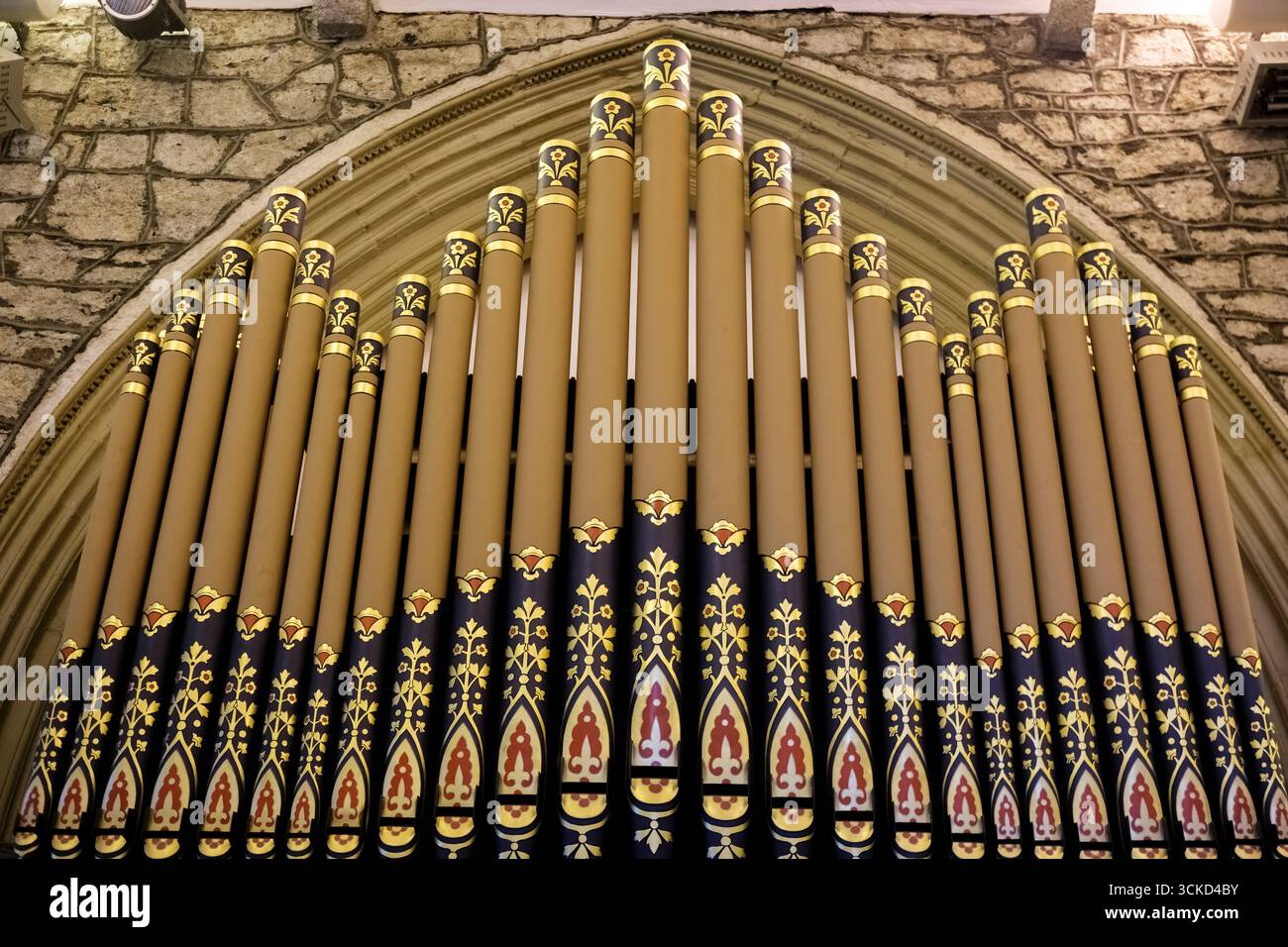 Les élégants tuyaux d'orgue ornés de motifs ornés s'élèvent majestueusement contre un mur de pierre rustique, évoquant un sentiment de vénération et de tranquillité dans cette sa Banque D'Images