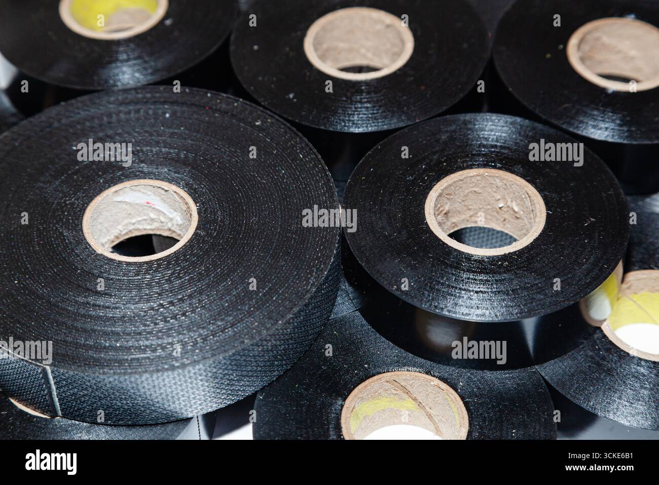 Plusieurs écheveaux de ruban électrique noir empilés les uns à côté des autres, gros plan. Banque D'Images