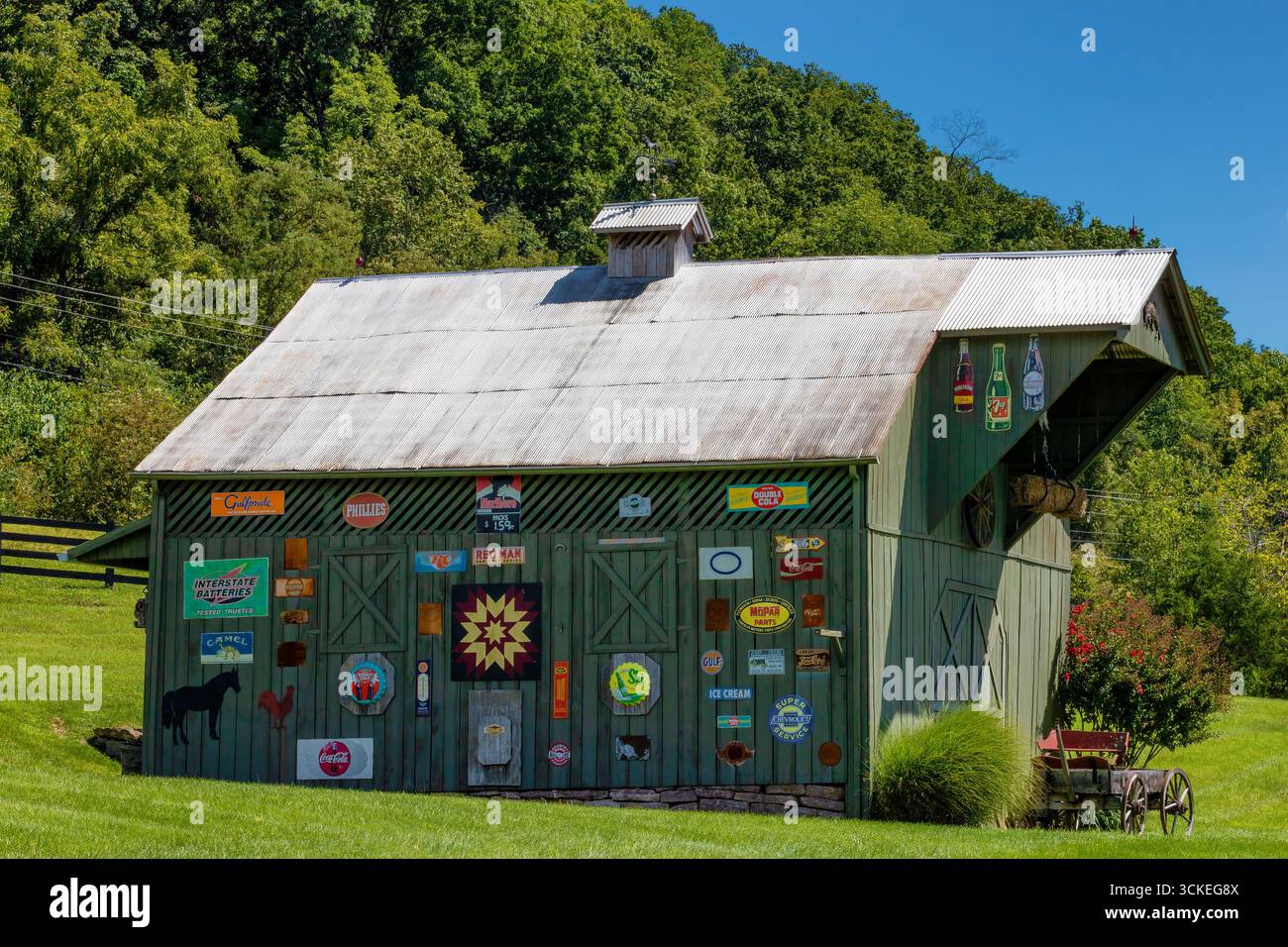 Rogersville, Tennessee, États-Unis - 27 août 2025 : une grange avec de vieilles enseignes et des articles avertissants penchant dessus et un vieux buggy garé près de ses portes. Banque D'Images