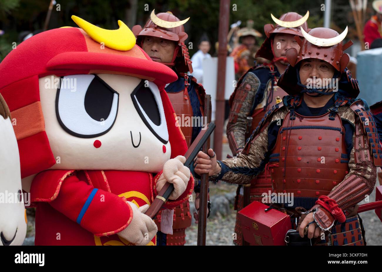 Des guerriers samouraïs du clan Hikone II en costume d'armure complet avec des fusils kabuto et à silex avec la mascotte Hikodon rejoignent l'événement, Hikone, Shiga, Japon. Banque D'Images