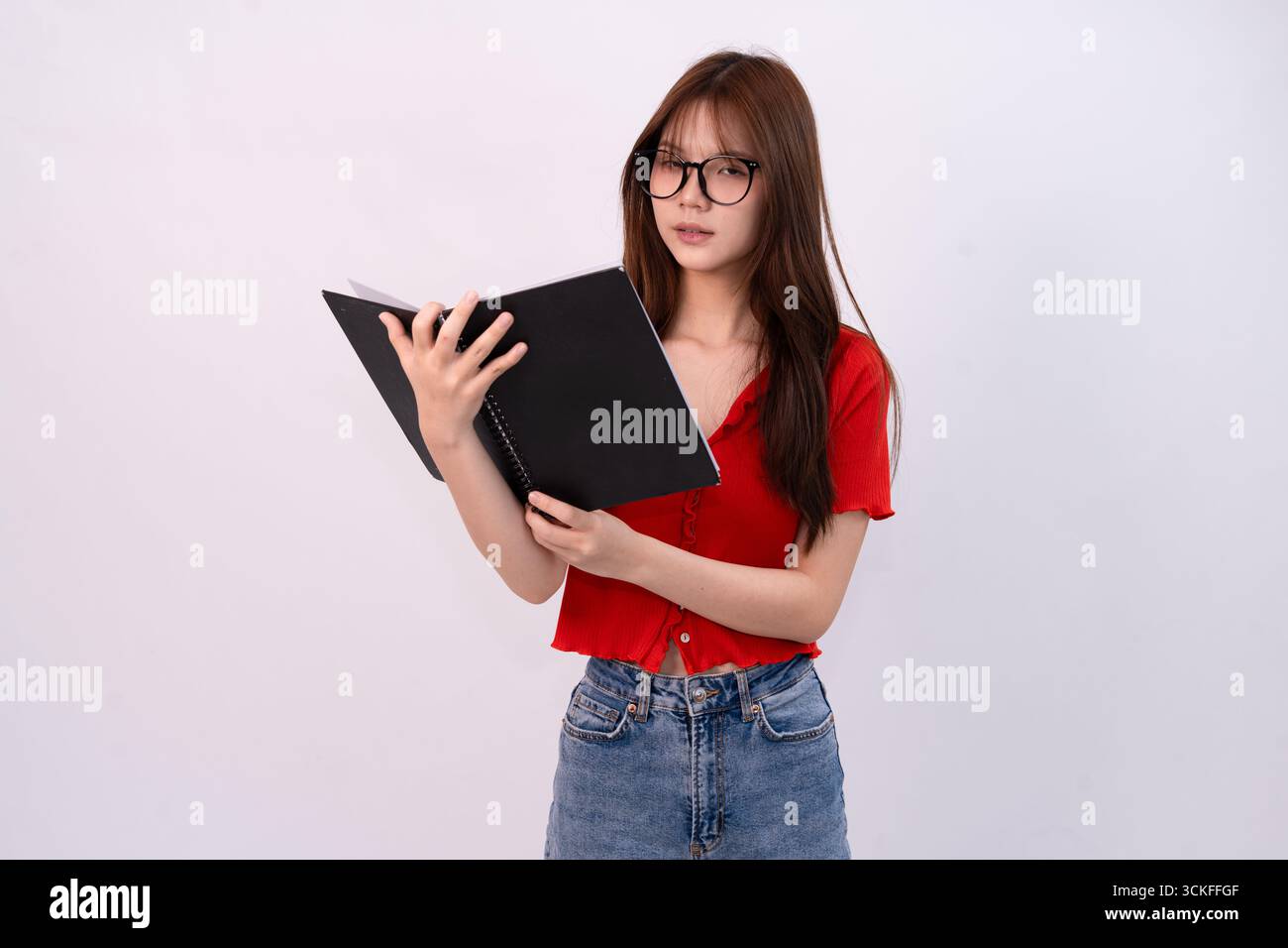 jeune belle femme lisant un cahier en tenue décontractée sur fond blanc studio Banque D'Images
