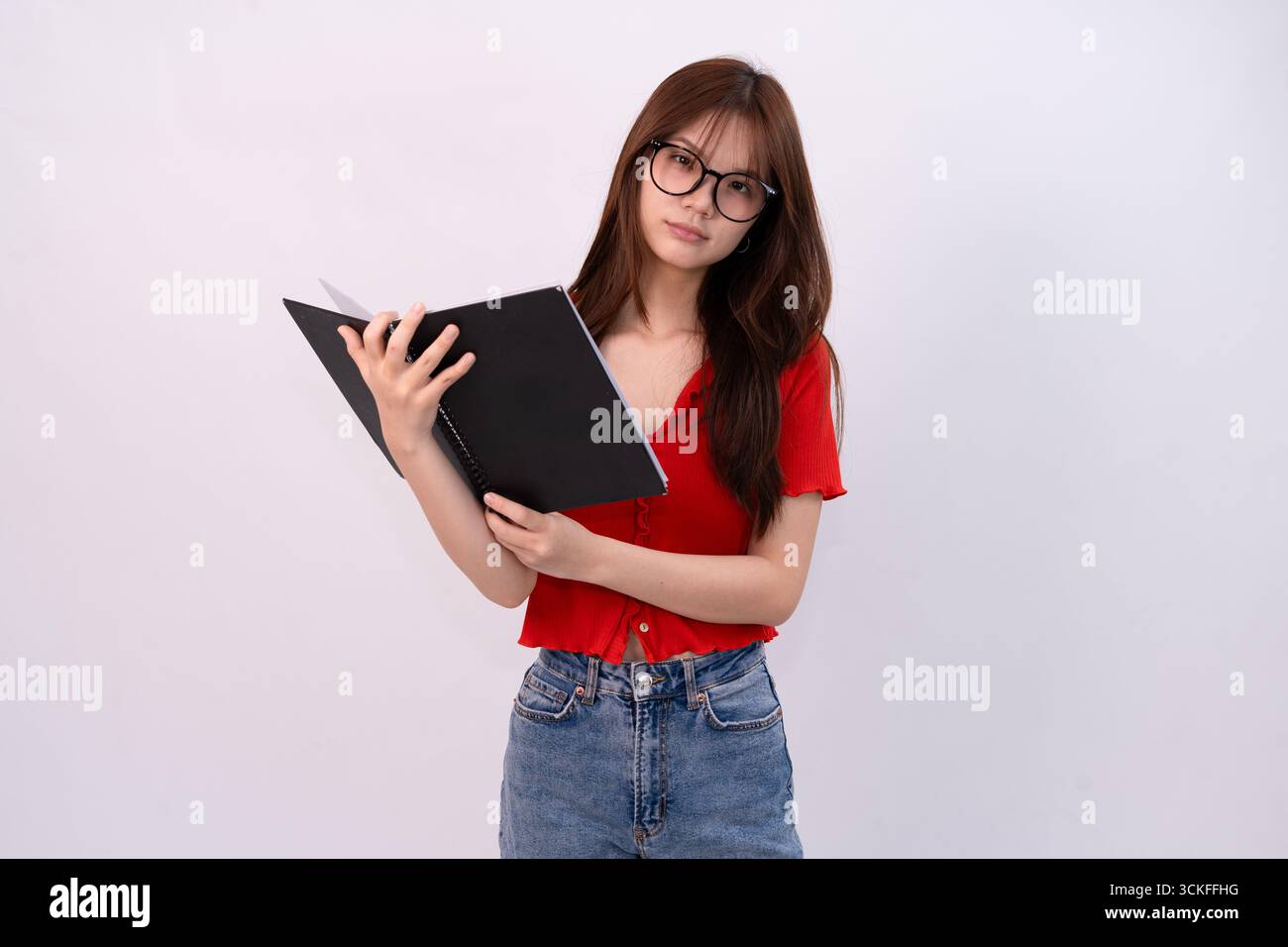 jeune belle femme lisant un cahier en tenue décontractée sur fond blanc studio Banque D'Images