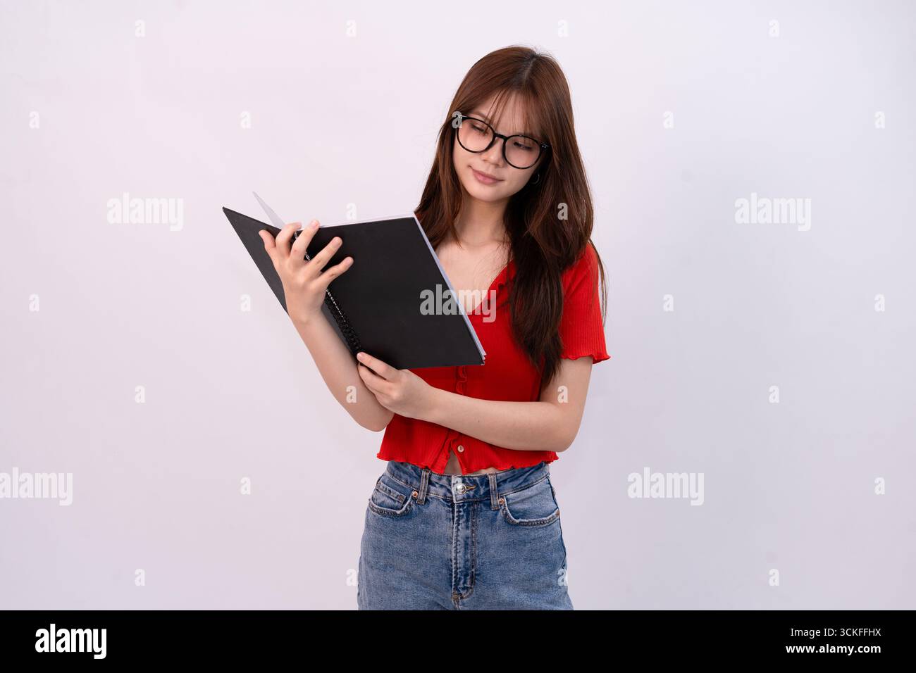 jeune belle femme lisant un cahier en tenue décontractée sur fond blanc studio Banque D'Images