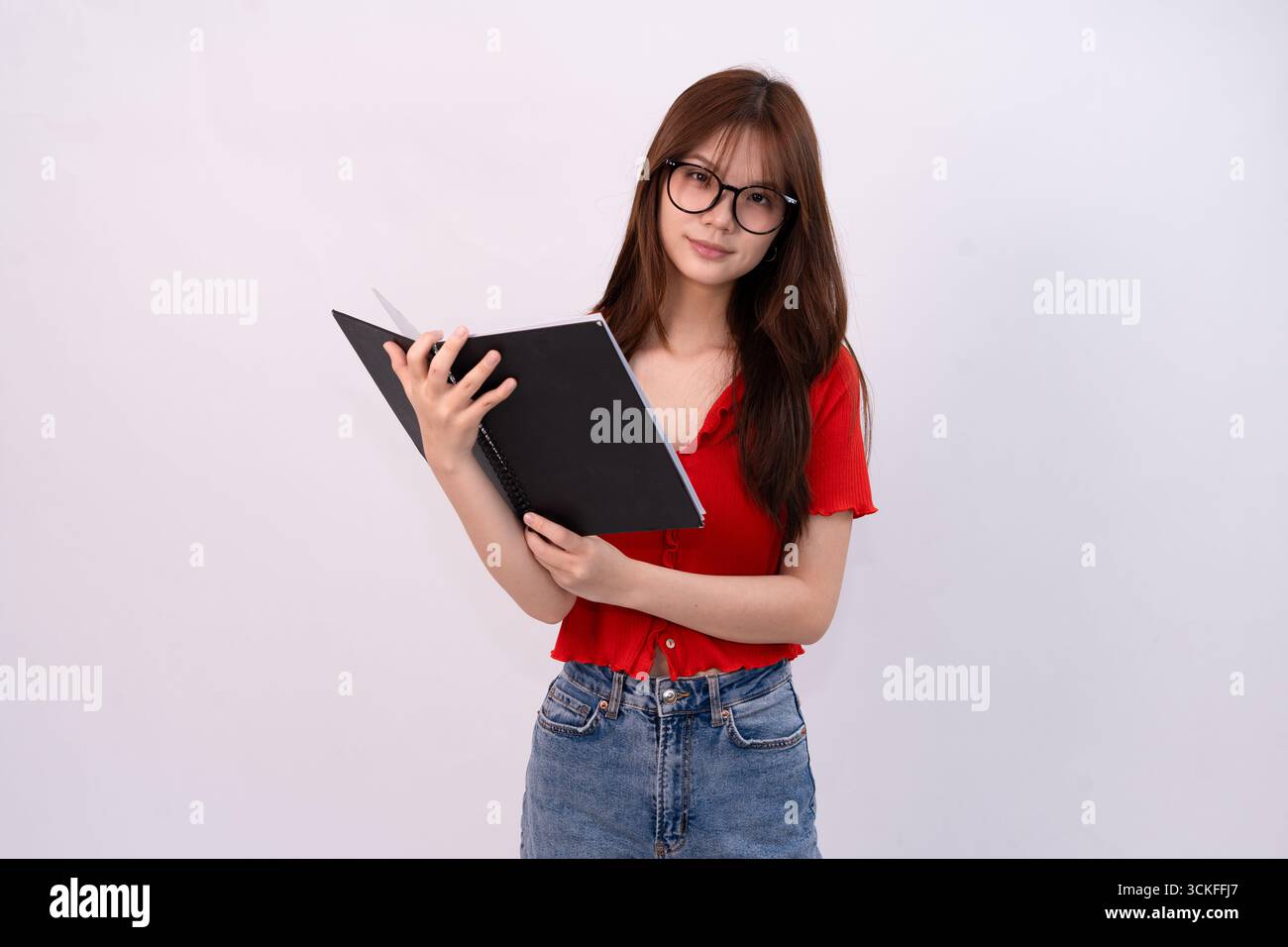 jeune belle femme lisant un cahier en tenue décontractée sur fond blanc studio Banque D'Images