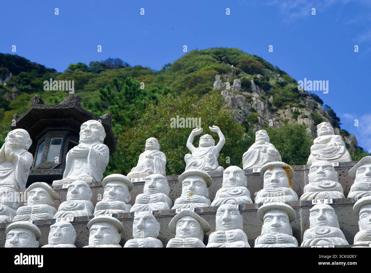 Des rangées de petites statues en pierre de disciples bouddhistes, chacune sculptée de manière unique, s'alignent sur des marches près du temple Bomunsa à la montagne Sanbangsan à Jeju. Banque D'Images