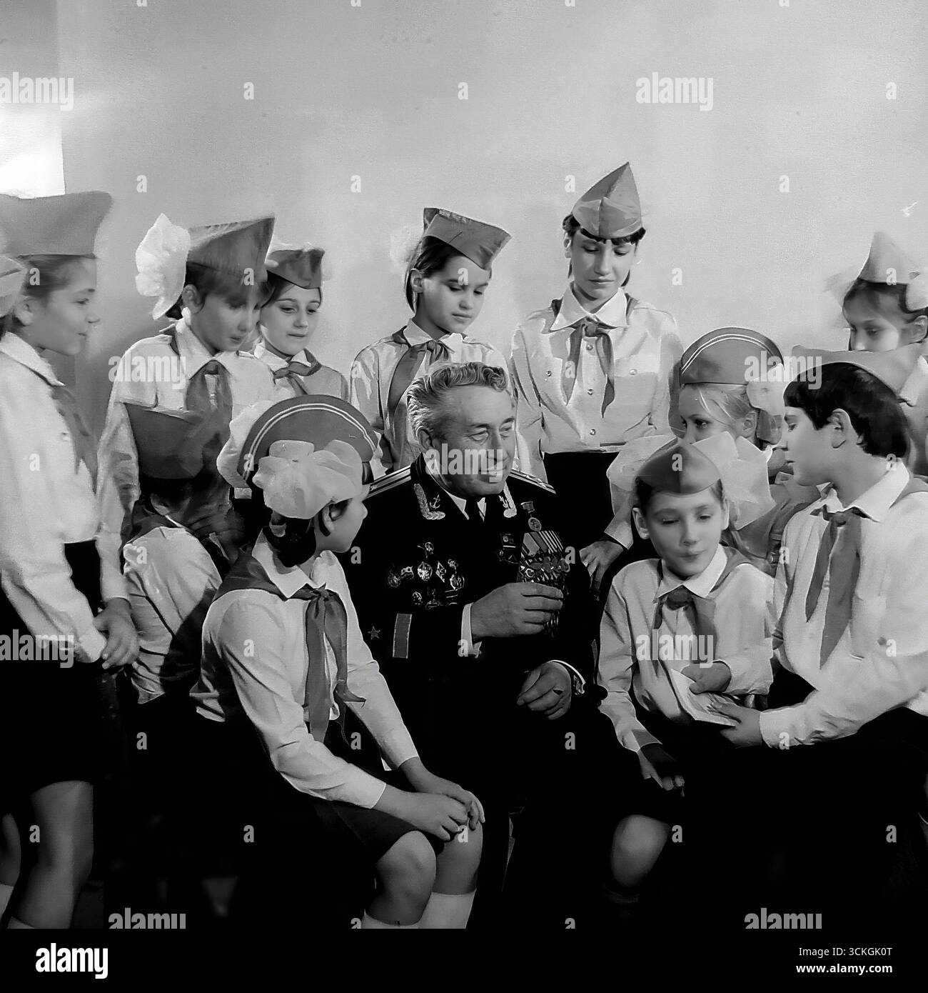 Une « leçon de courage » à l'école secondaire n ° 12 à Sloviansk à la fin des années 1970 L'instructeur militaire de l'école (voenruk), un vétéran distingué de la Grande Guerre patriotique, est entouré d'étudiants d'un club patriotique, tous en uniforme. Il leur montre ses récompenses militaires et partage les histoires derrière eux. Cette photographie symbolise profondément le système soviétique de formation militaire de base (NVP) et les vastes programmes d'éducation patriotique conçus pour inculquer le respect de la mémoire militaire et historique à la jeune génération Banque D'Images