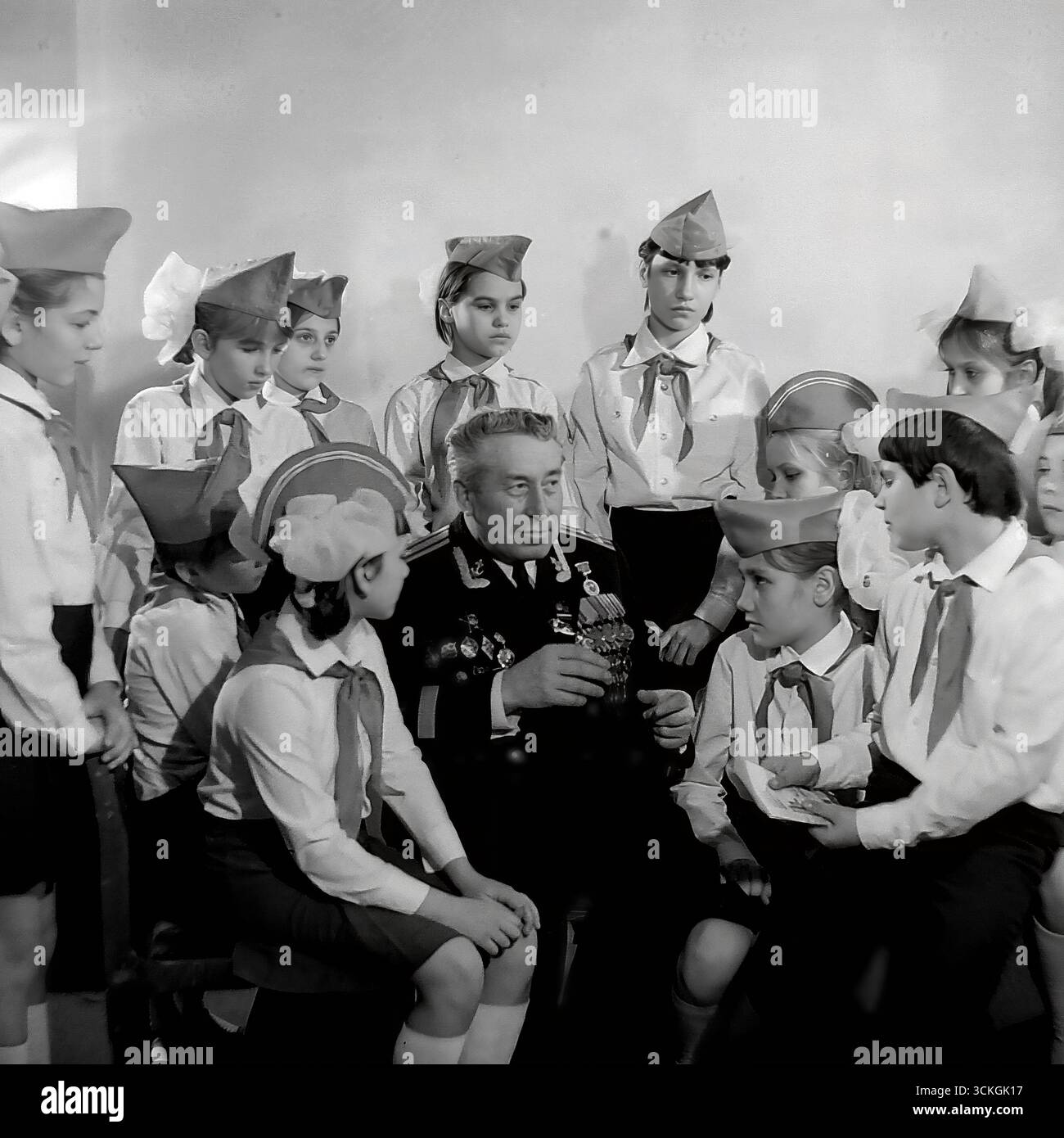 Une « leçon de courage » à l'école secondaire n ° 12 à Sloviansk à la fin des années 1970 L'instructeur militaire de l'école (voenruk), un vétéran distingué de la Grande Guerre patriotique, est entouré d'étudiants d'un club patriotique, tous en uniforme. Il leur montre ses récompenses militaires et partage les histoires derrière eux. Cette photographie symbolise profondément le système soviétique de formation militaire de base (NVP) et les vastes programmes d'éducation patriotique conçus pour inculquer le respect de la mémoire militaire et historique à la jeune génération Banque D'Images