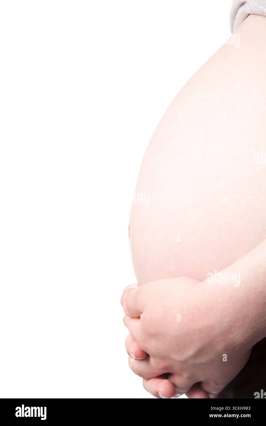 Ventre enceinte tendu tendrement par les mains, symbolisant l'amour maternel, la protection et l'anticipation sereine de la maternité Banque D'Images