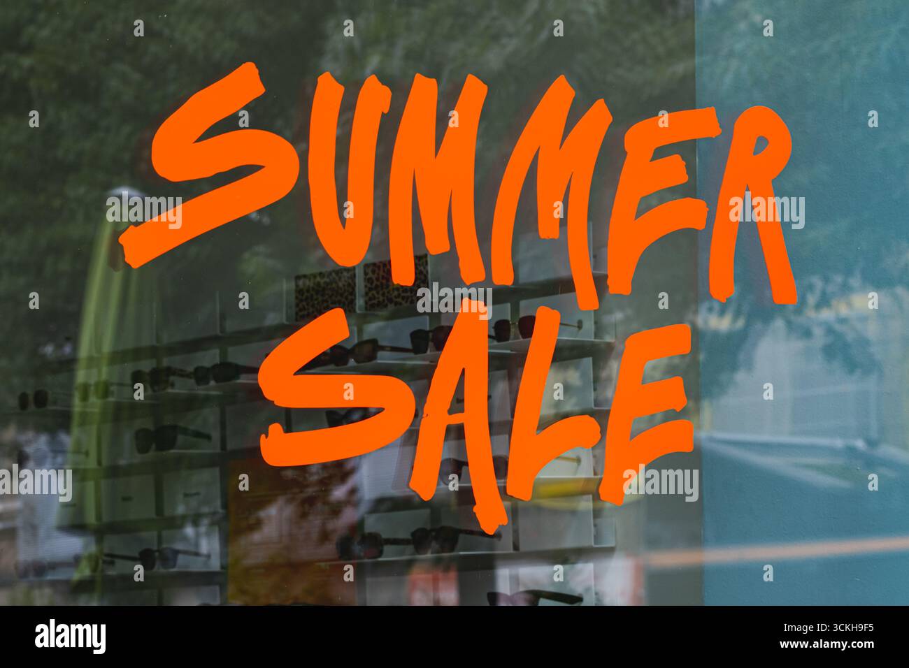 Signe de vente d'été orange vif en lettrage moderne à main levée sur une vitrine de magasin Banque D'Images