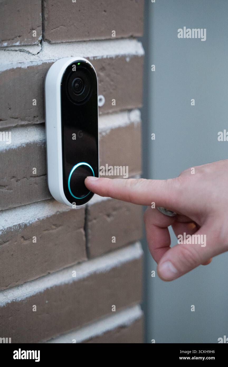 Un utilisateur appuie sur un bouton de sonnette intelligent, qui présente les dernières avancées technologiques de sécurité domestique moderne Banque D'Images