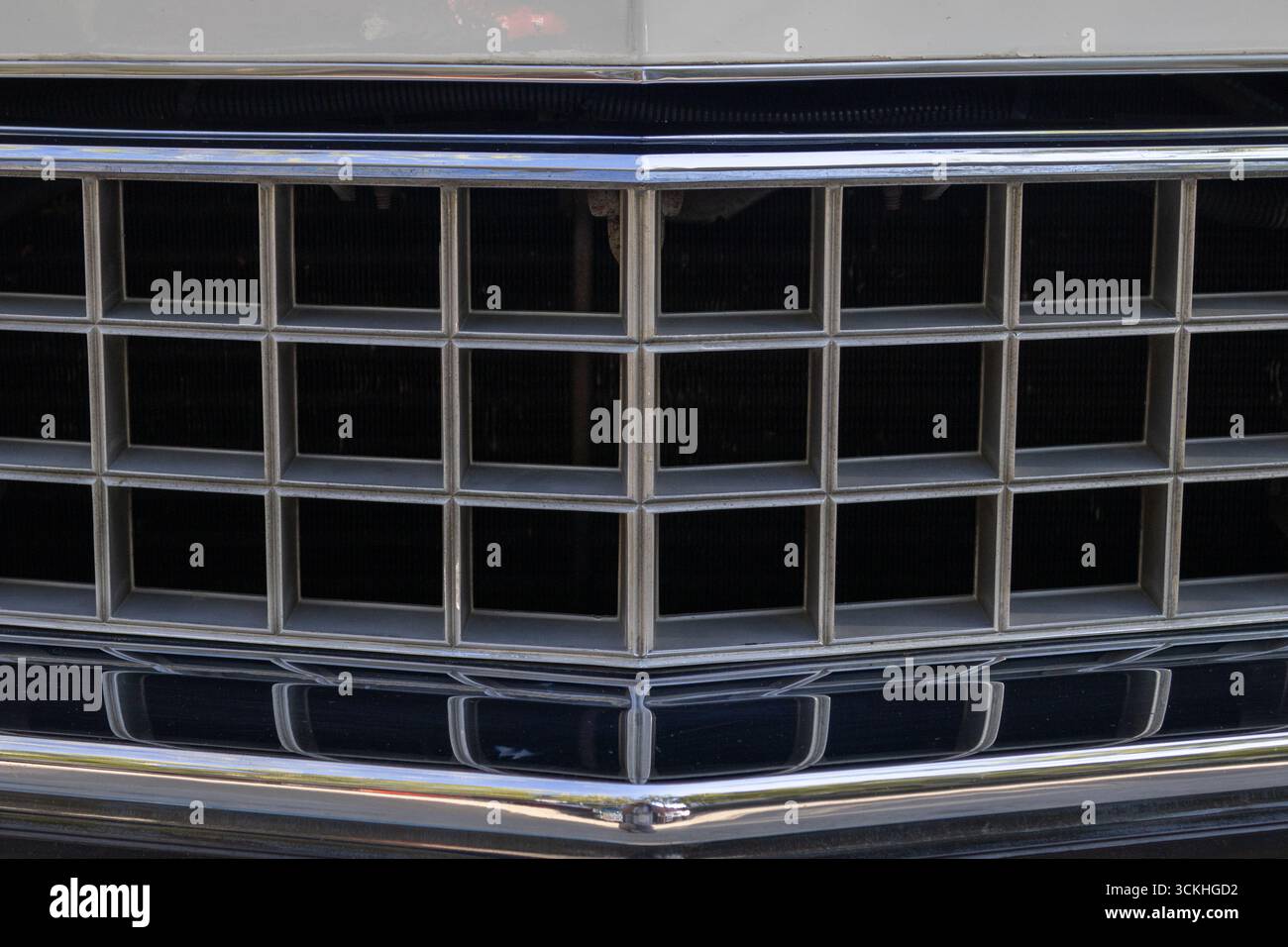 Gros plan d'une calandre chromée brillante sur une voiture d'époque, reflétant le ciel et évoquant une ère révolue du design automobile Banque D'Images