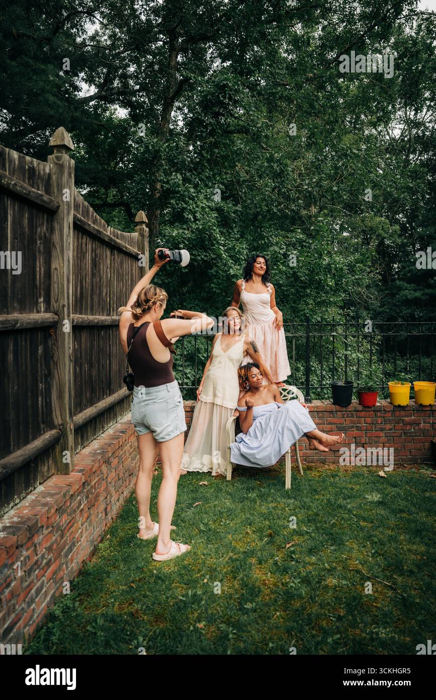 Photographe prenant des photos de trois mannequins de mode dans le jardin Banque D'Images