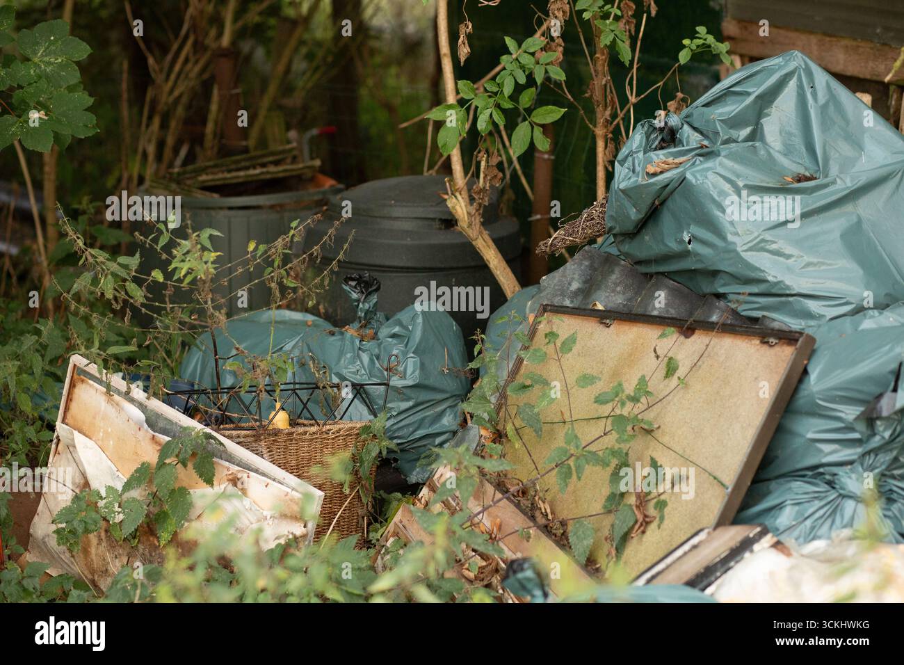 Gros plan de sacs poubelle verts attachés avec des feuilles à l'avant, texture brute de pollution environnementale. Banque D'Images