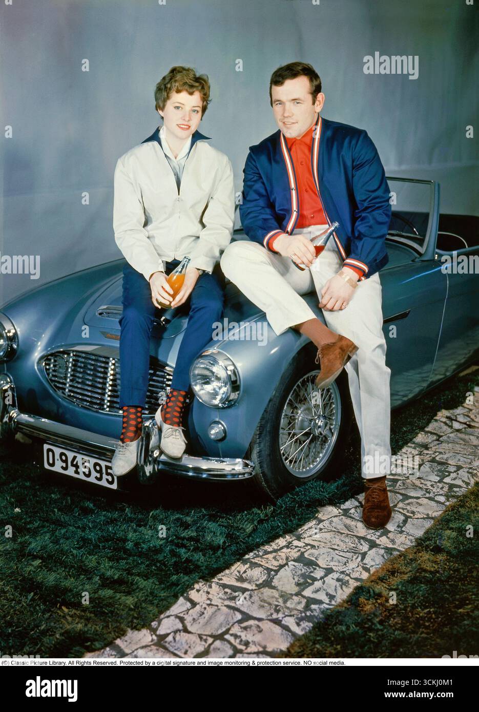 Ingemar Johansson et Birgit Lundgren avec l'Austin-Healey 3000Dans ce cliché emblématique de 1959, le champion suédois de boxe poids lourds Ingemar 'Ingo' Johansson (1932-2009) et sa fiancée Birgit Lundgren sont assis au sommet d'une Austin-Healey 3000, une voiture de sport britannique de premier plan. Introduite en 1959 par la Donald Healey Motor Company sous BMC, la 3000 était équipée d'un moteur six cylindres en ligne de 2,9 litres pouvant atteindre 150 ch, de freins à disque et d'une vitesse de pointe supérieure à 120 km/h, alliant performance et élégance. Fraîchement sorti de son superbe knockout de 1959 de Floyd Patterson pour revendiquer le titre des poids lourds, Johansson incarnait la célébrité g. Banque D'Images