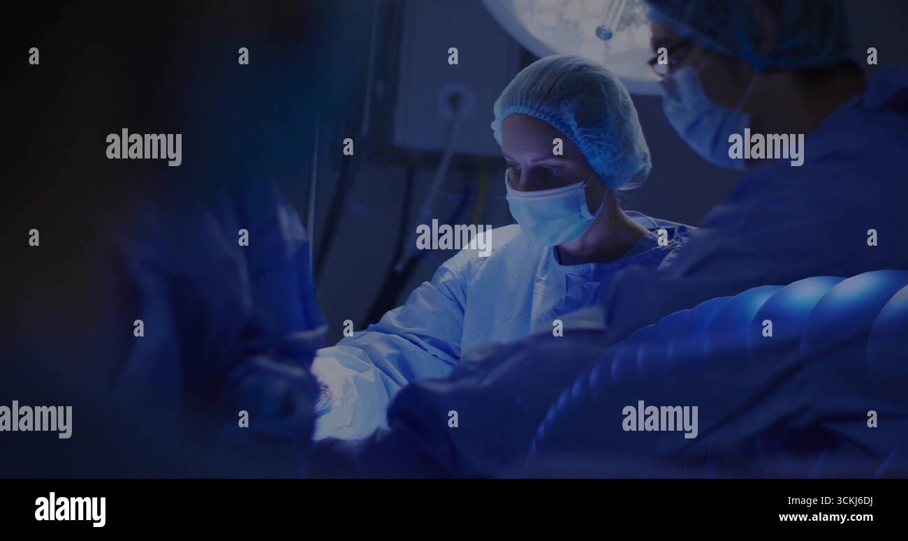 Chirurgienne pratiquant l'opération portant une blouse penchée sur le champ adhésif du patient dans LE BLOC OPÉRATOIRE, instruments sous la lampe Banque D'Images