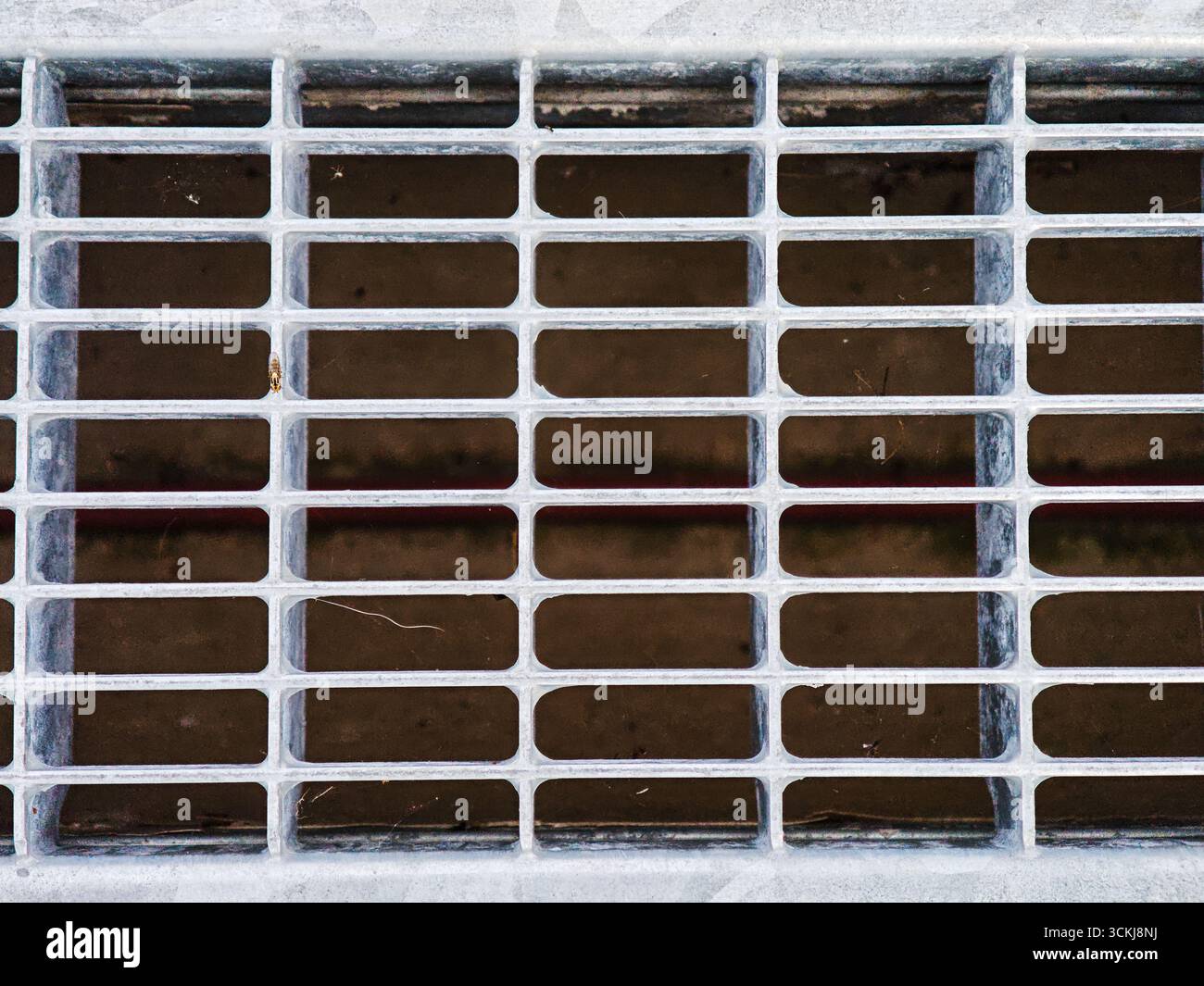 Grille de drainage en métal avec motif de grille rectangulaire sur fond sombre. Photo de haute qualité Banque D'Images