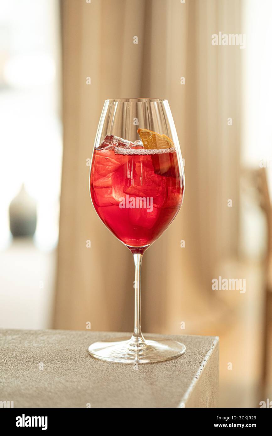 Cocktail rouge avec orange et glace dans un verre à vin Banque D'Images