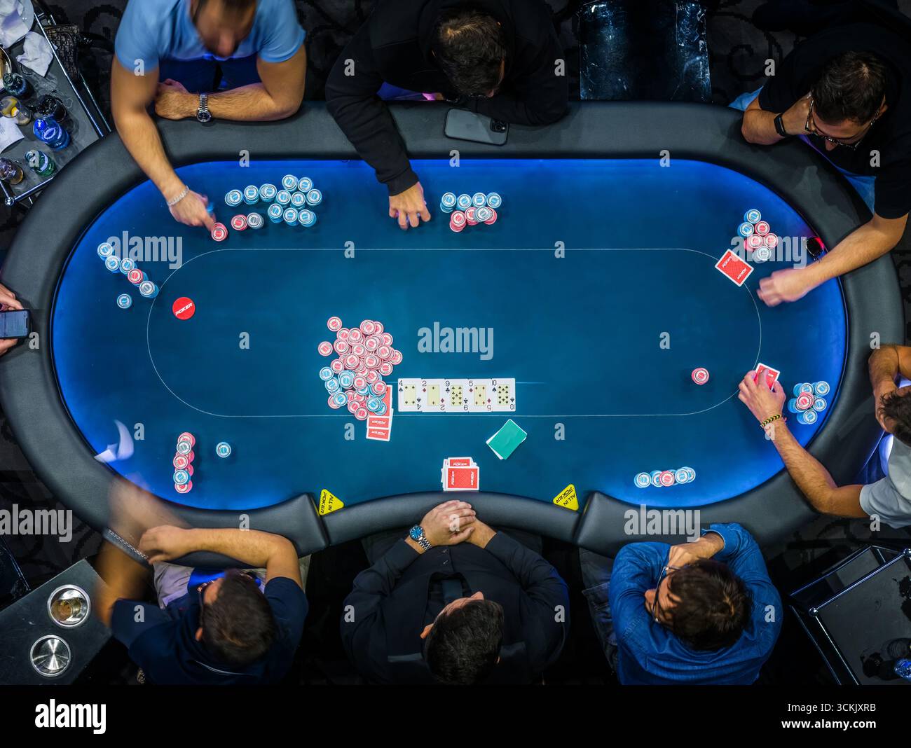 Vue de haut en bas d'un jeu de poker à enjeux élevés dans un casino avec des joueurs engagés dans des stratégies sérieuses et une concentration intense Banque D'Images