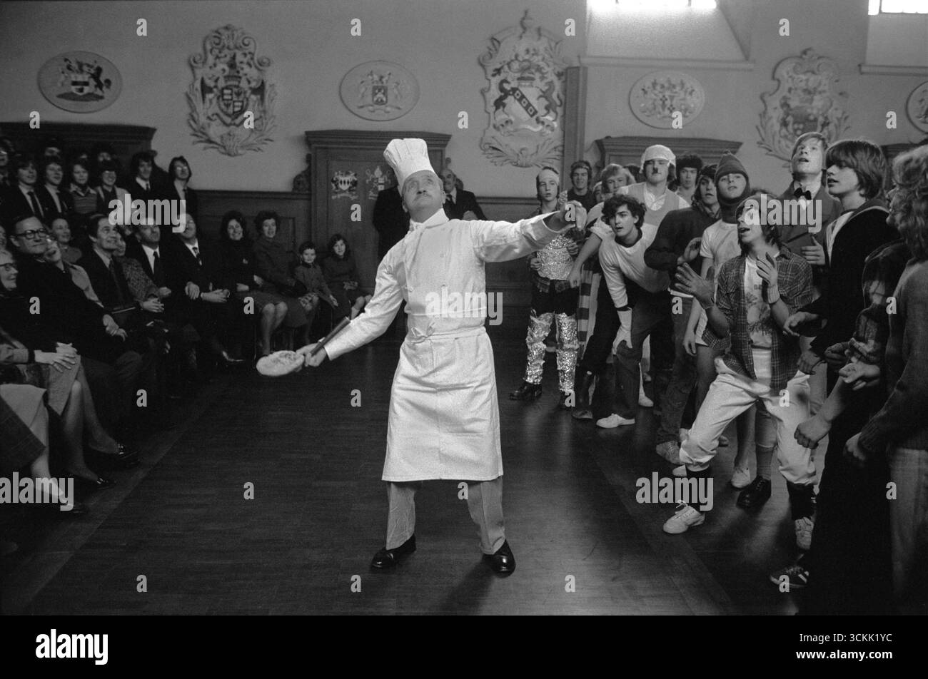 Westminster School Shrove Tuesday Pancake Greaze. Chef Sam Sellars. jette la crêpe. Des garçons qui se préparent à se bousculer pour un morceau de crêpe. Westminster, Londres, Angleterre 1976 1970S Royaume-Uni HOMER SYKES Banque D'Images
