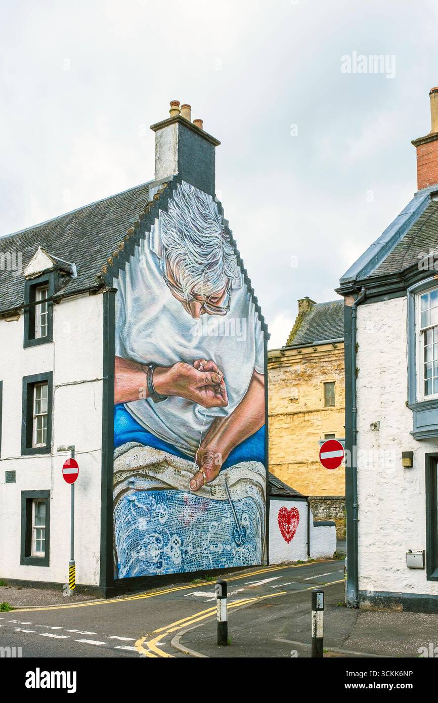 Peinture murale d'une femme cousant une couverture de table en dentelle, peinte sur le mur d'extrémité de vent d'un bâtiment du XIXe siècle, Newmilns, Ayrshire, Écosse. Peint en hommage Banque D'Images