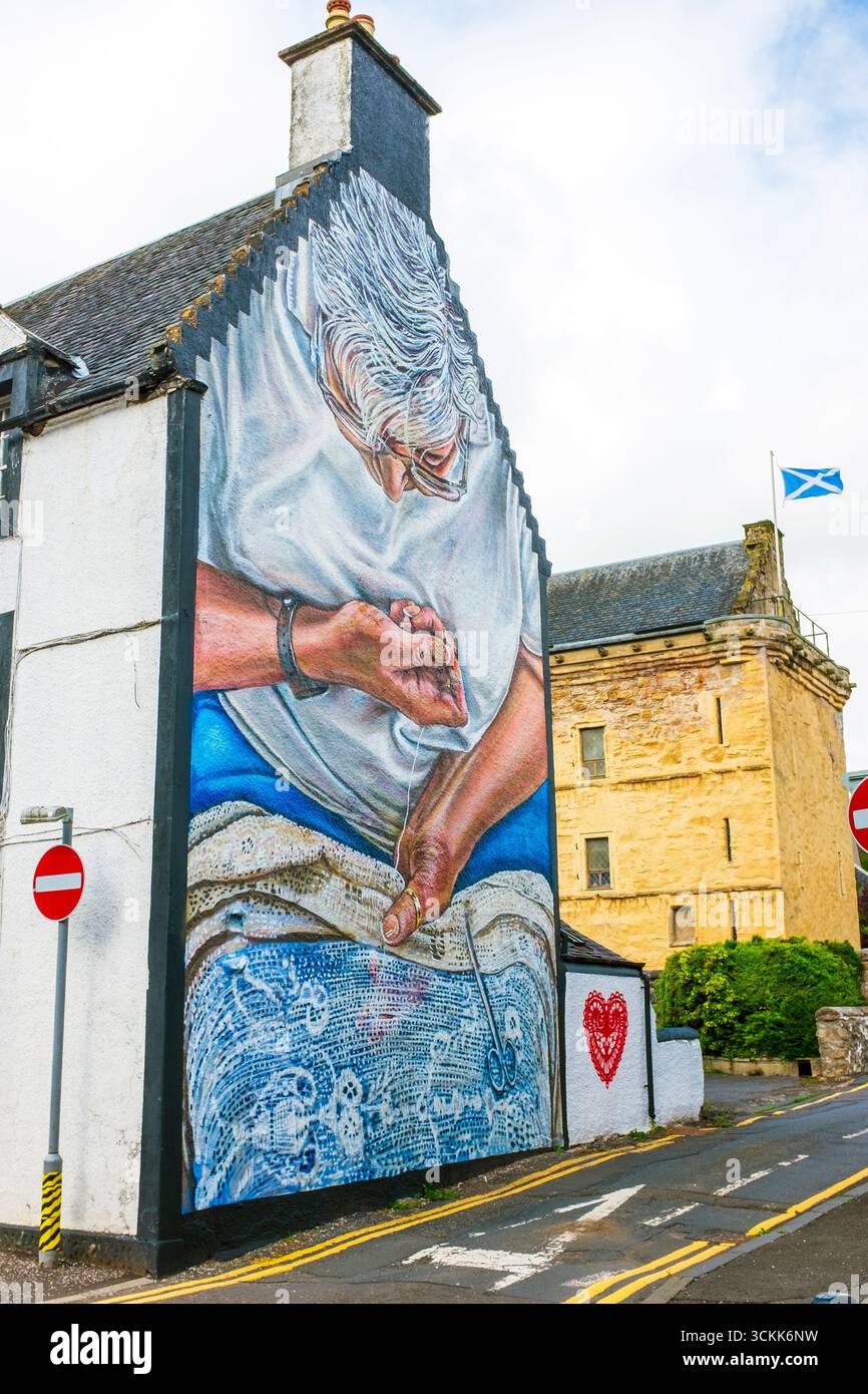 Peinture murale d'une femme cousant une couverture de table en dentelle, peinte sur le mur d'extrémité de vent d'un bâtiment du XIXe siècle, Newmilns, Ayrshire, Écosse. Peint en hommage Banque D'Images