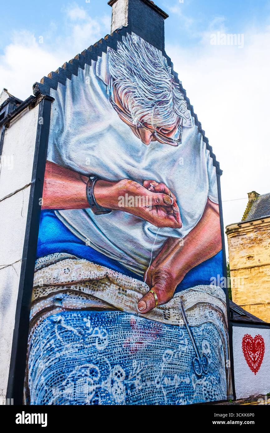 Peinture murale d'une femme cousant une couverture de table en dentelle, peinte sur le mur d'extrémité de vent d'un bâtiment du XIXe siècle, Newmilns, Ayrshire, Écosse. Peint en hommage Banque D'Images