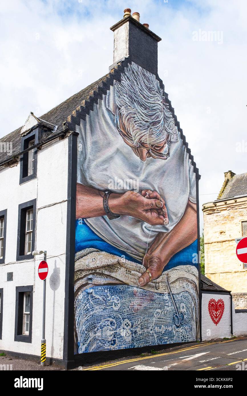 Peinture murale d'une femme cousant une couverture de table en dentelle, peinte sur le mur d'extrémité de vent d'un bâtiment du XIXe siècle, Newmilns, Ayrshire, Écosse. Peint en hommage Banque D'Images