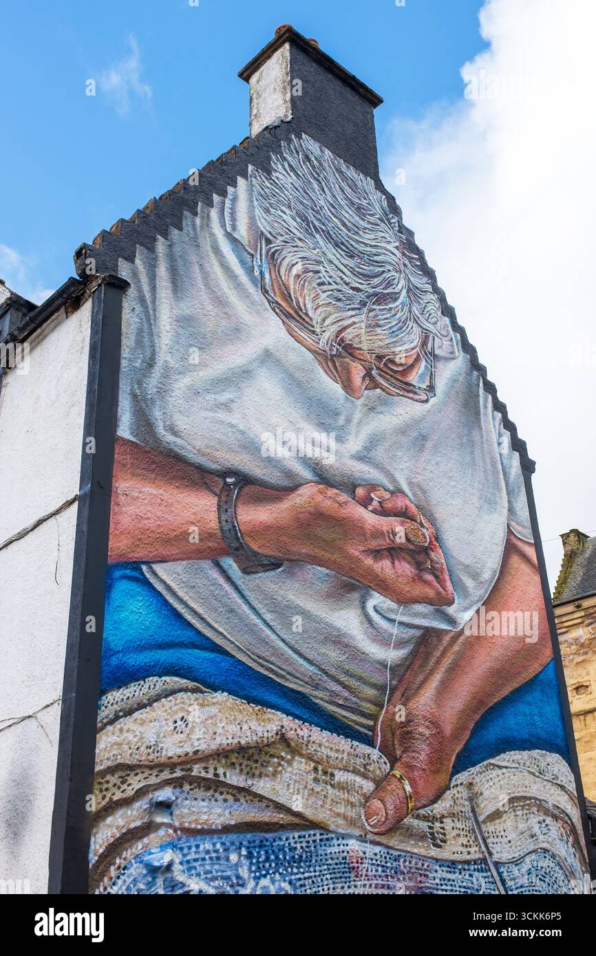 Peinture murale d'une femme cousant une couverture de table en dentelle, peinte sur le mur d'extrémité de vent d'un bâtiment du XIXe siècle, Newmilns, Ayrshire, Écosse. Peint en hommage Banque D'Images