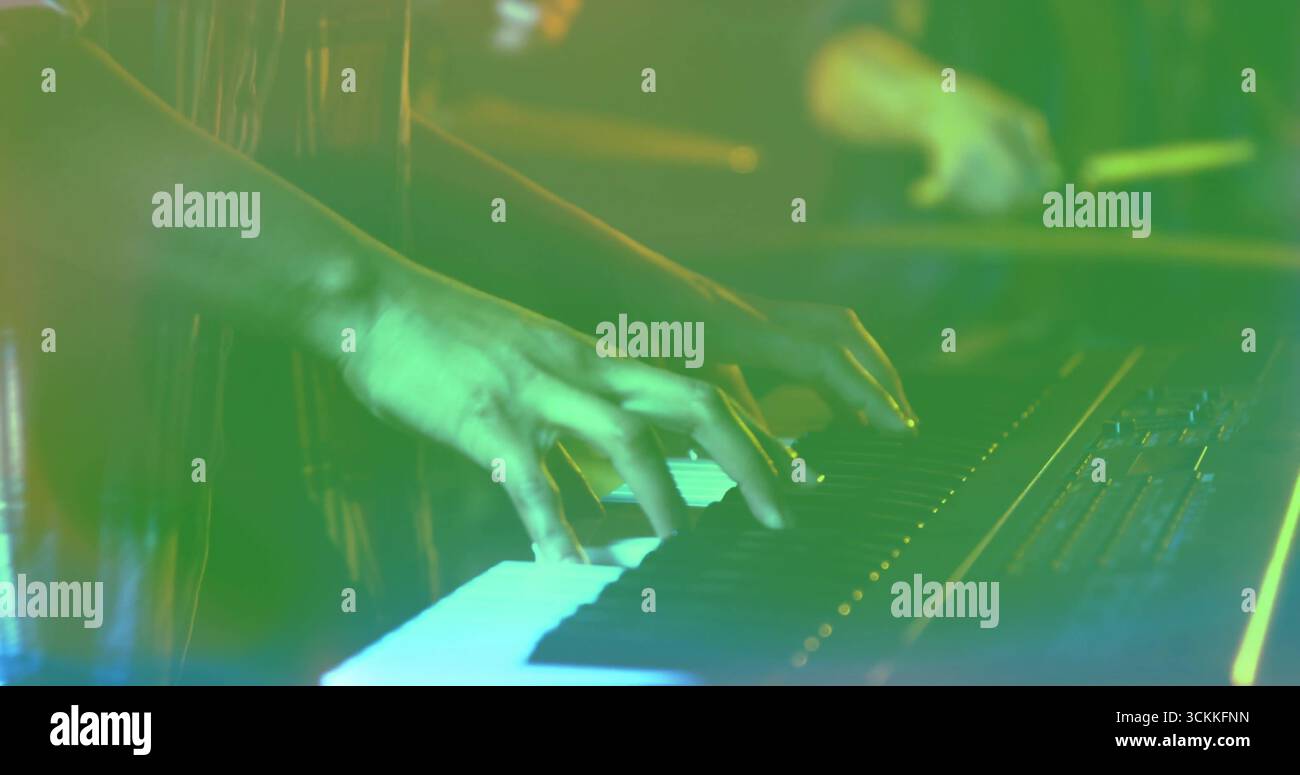 Appuyant sur les mains du clavier jouant synthétiseur sur la scène de concert, avec baguettes de batterie et éclairage vert Banque D'Images