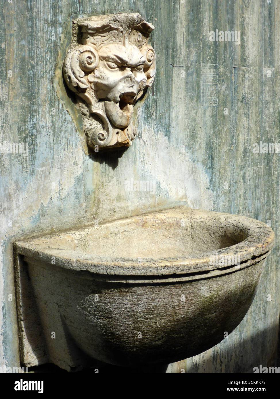 Fontaine en pierre ornée à Lisbonne présente un visage d'une figure mythologique avec bouche ouverte, servant de bec d'eau. Le bassin altéré est semi-circulaire Banque D'Images