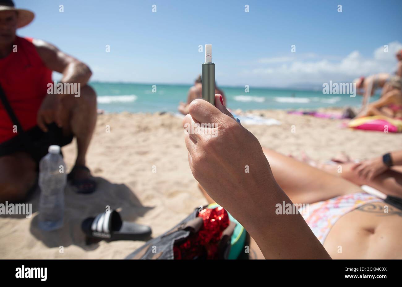 Palma, Espagne. 12 septembre 2025. Une femme montre une e-cigarette en prenant un bain de soleil sur la plage d'Arenal. Un projet de loi visant à étendre les zones sans fumée a été adopté en Espagne cette semaine. Crédit : Clara Margais/dpa/Alamy Live News Banque D'Images