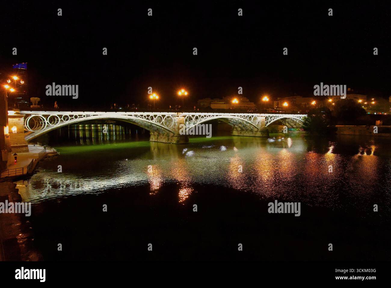 Vue nocturne du pont routier Isabel II illuminé sur la rivière Guadalquivir dans le centre-ville de Séville Andalousie Espagne Europe Banque D'Images