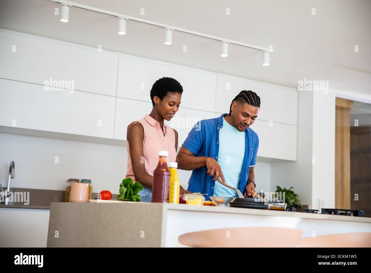 Divers couples de cuisson des légumes dans une poêle à frire sur l'îlot de cuisine avec tomate et planche à découper Banque D'Images Divers couples de cuisson des légumes dans une poêle à frire sur l'îlot de cuisine avec tomate et planche à découper Banque D'Images