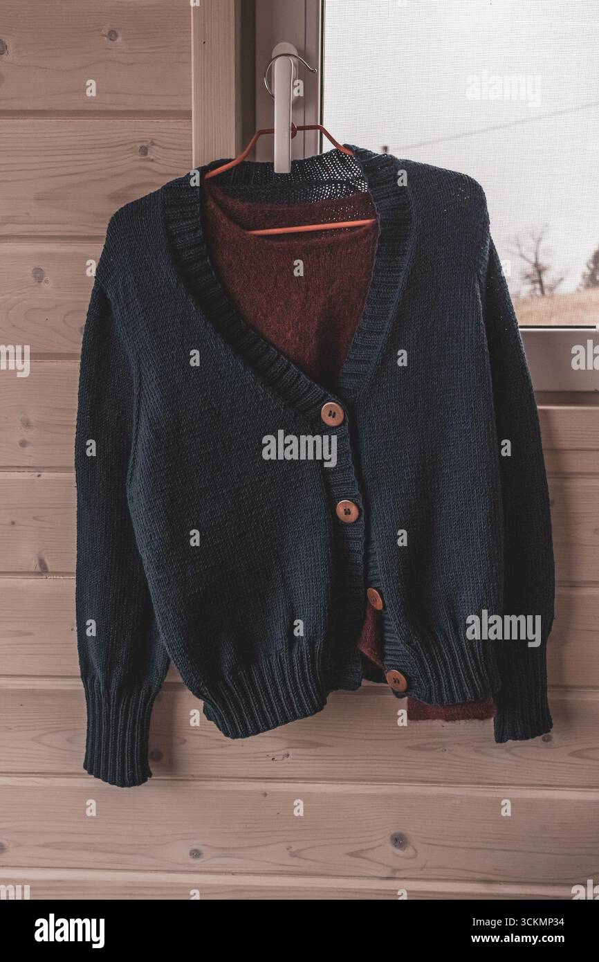 Des choses tricotées à la main. Cardigan tricoté. Des choses chaudes. Garde-robe d'automne. Produits en laine. Pull en laine. Vêtements sur un cintre. Chambre des femmes. Banque D'Images