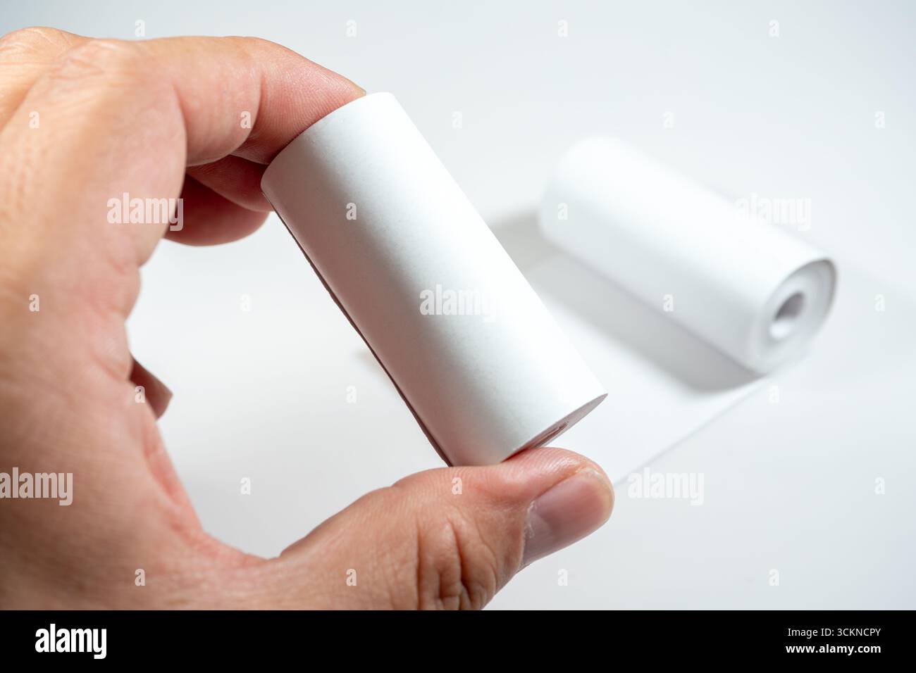 Main tenant un rouleau de papier thermique, symbolisant le contact direct de la peau avec le revêtement chimique du papier, qui peut contenir du BPA (bisphénol A) Banque D'Images