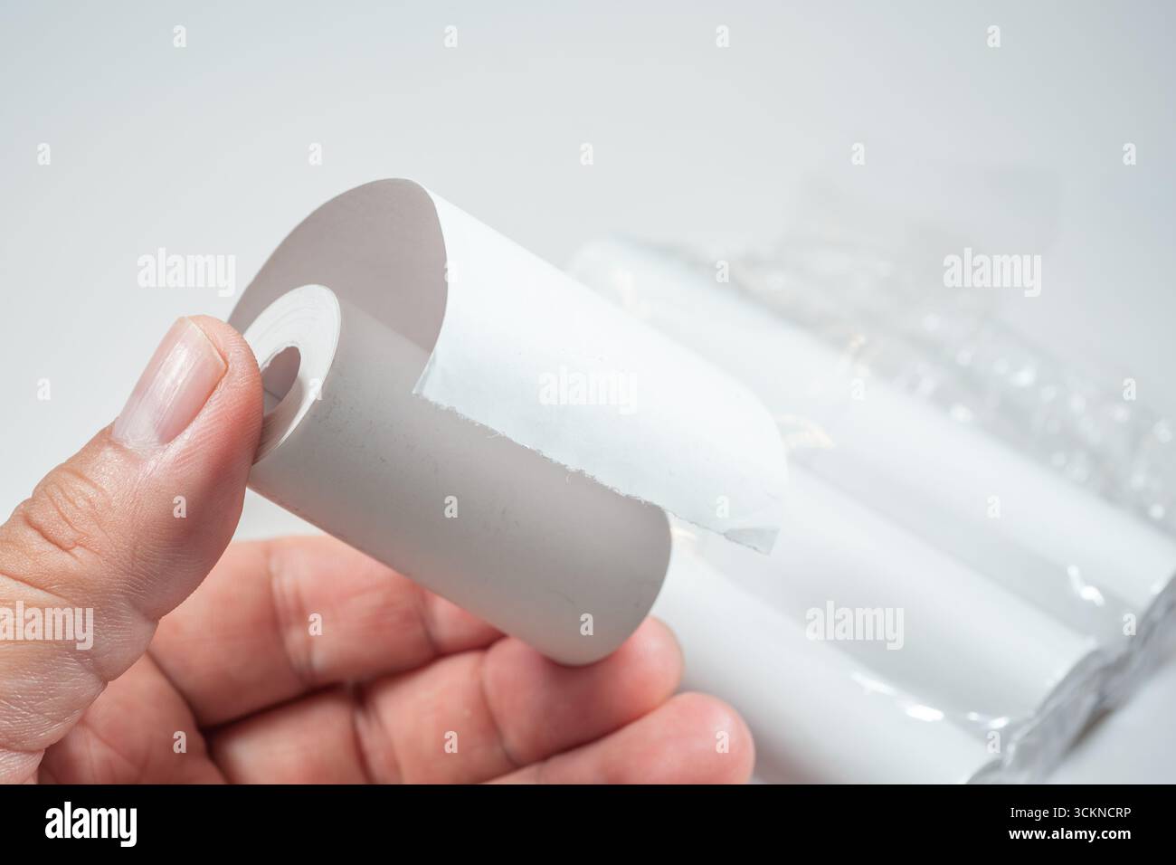 Main tenant un rouleau de papier thermique, symbolisant le contact direct de la peau avec le revêtement chimique du papier, qui peut contenir du BPA (bisphénol A) Banque D'Images